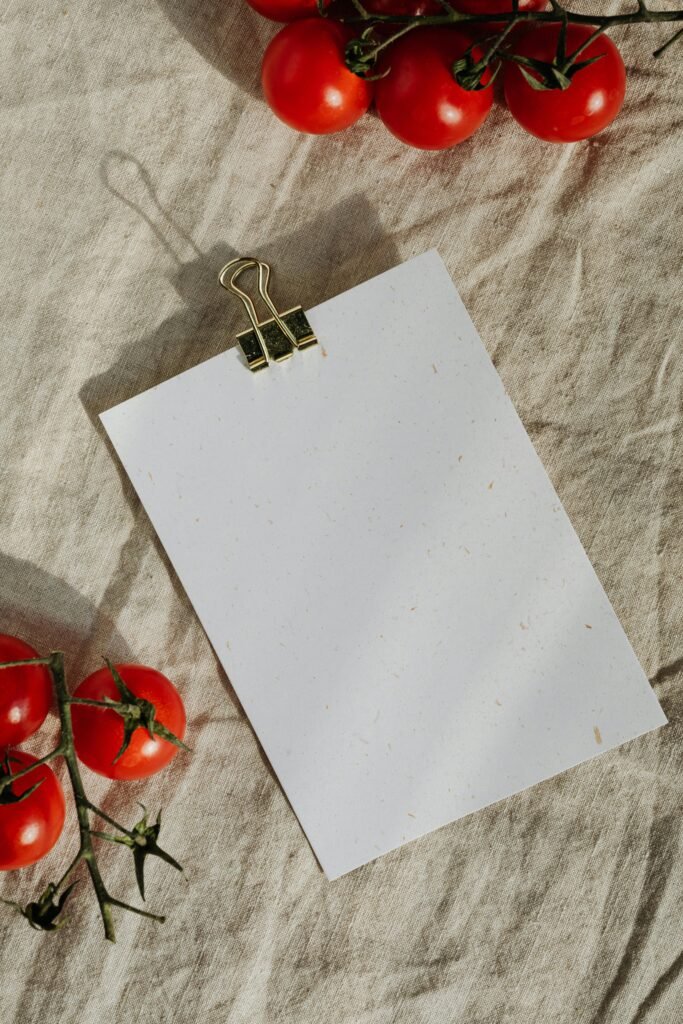 Blank sheet of paper with tomatoes on linen cloth, perfect for a food-themed flat lay.